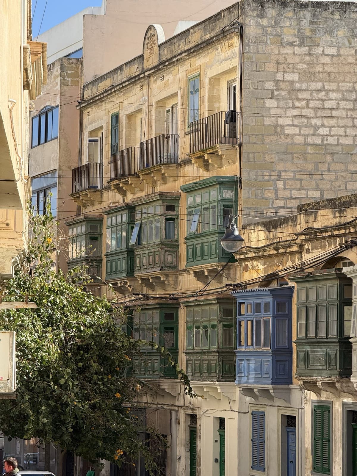 Green and blue gallarija balconies on limestone townhouses in Malta