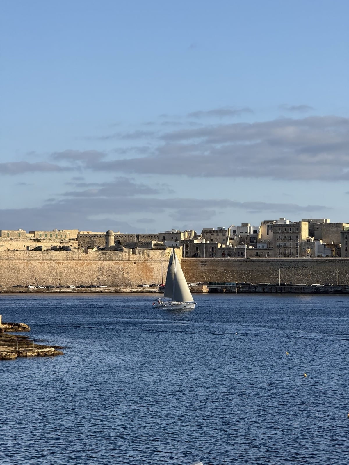 A sailboat passing beneath the bastion walls of Valletta